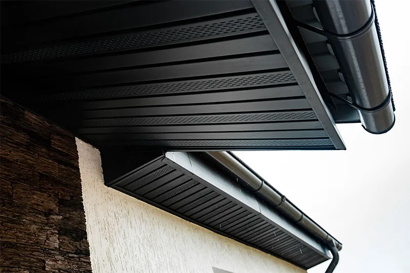 Black gutter, fascia and vented soffit on a house with stone and stucco walls