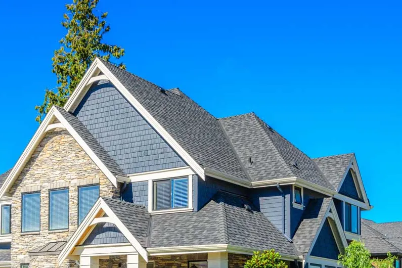 Blue house with stone accents under a gray shingle roof