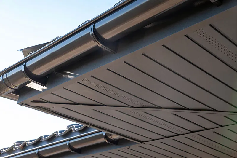 Dark gutter along an eave above gray vented soffit panels
