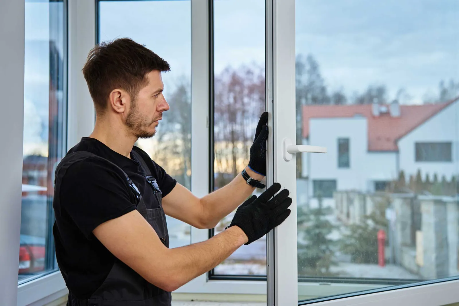 Installer in work gloves fitting a new window into its frame