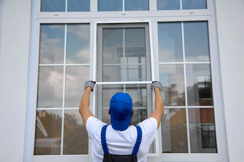 Installer setting a large new window into its opening from inside the house