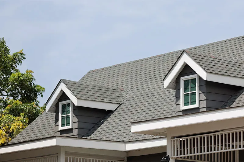 Gray shingle roof with two dormers over dark siding