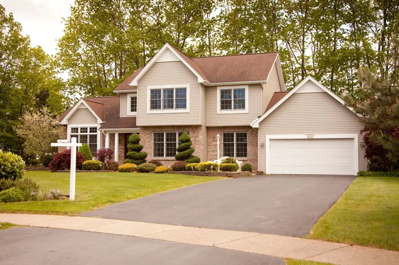 Two-story house with beige siding, a brick front and an attached garage