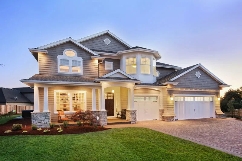 Large two-story house with lit windows at dusk