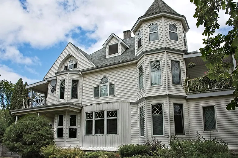 Large Victorian house with a corner turret and cream siding
